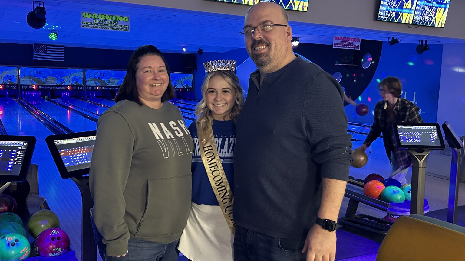 Mom and dad posing with their daughter at VU's bowling center during parent and family weekend