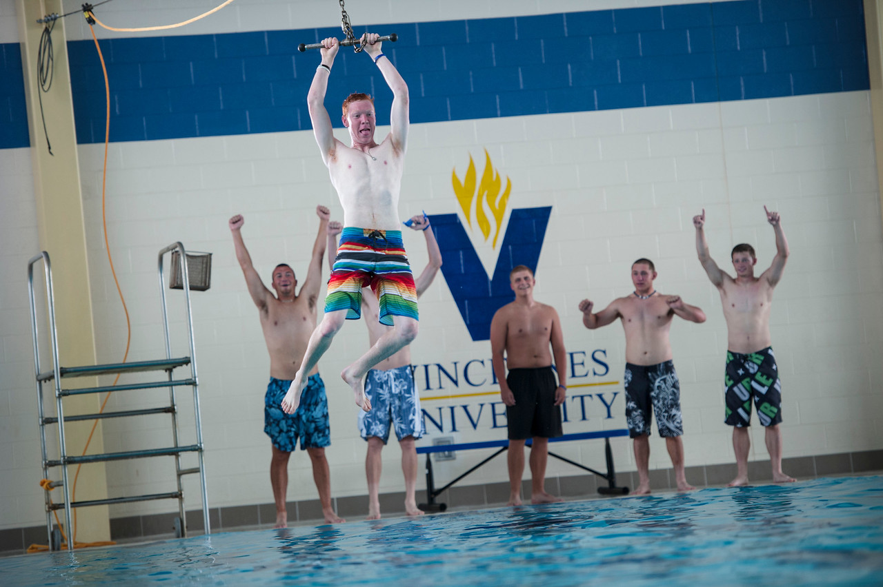 6 male students playing at the aquatic center using the tee bar swing.