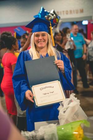 An ABE graduate shows off her diploma