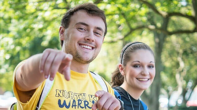 Male student pointing at the photographer while walking with a female classmate