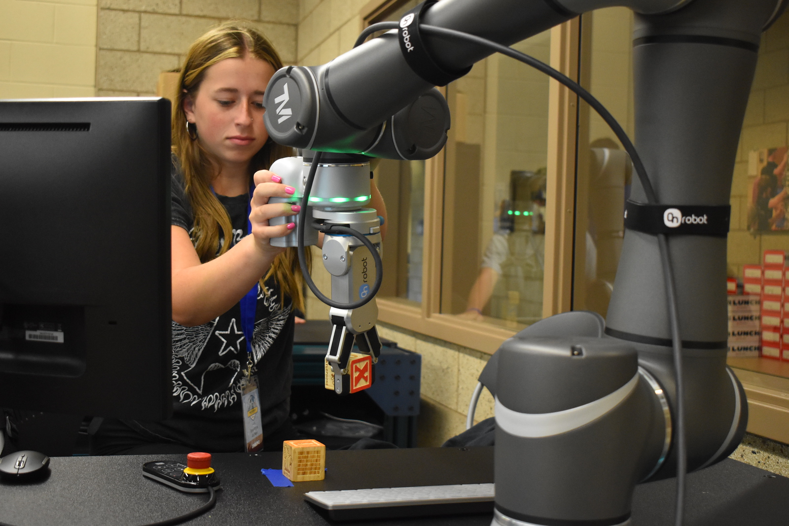 A female student using a mechanical arm to pick up wooden blocks