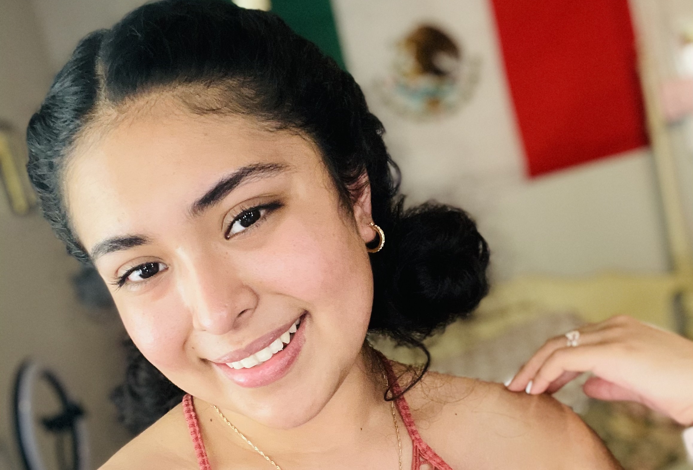 Perla Maldonado smiles for the camera with a Mexican flag in the background