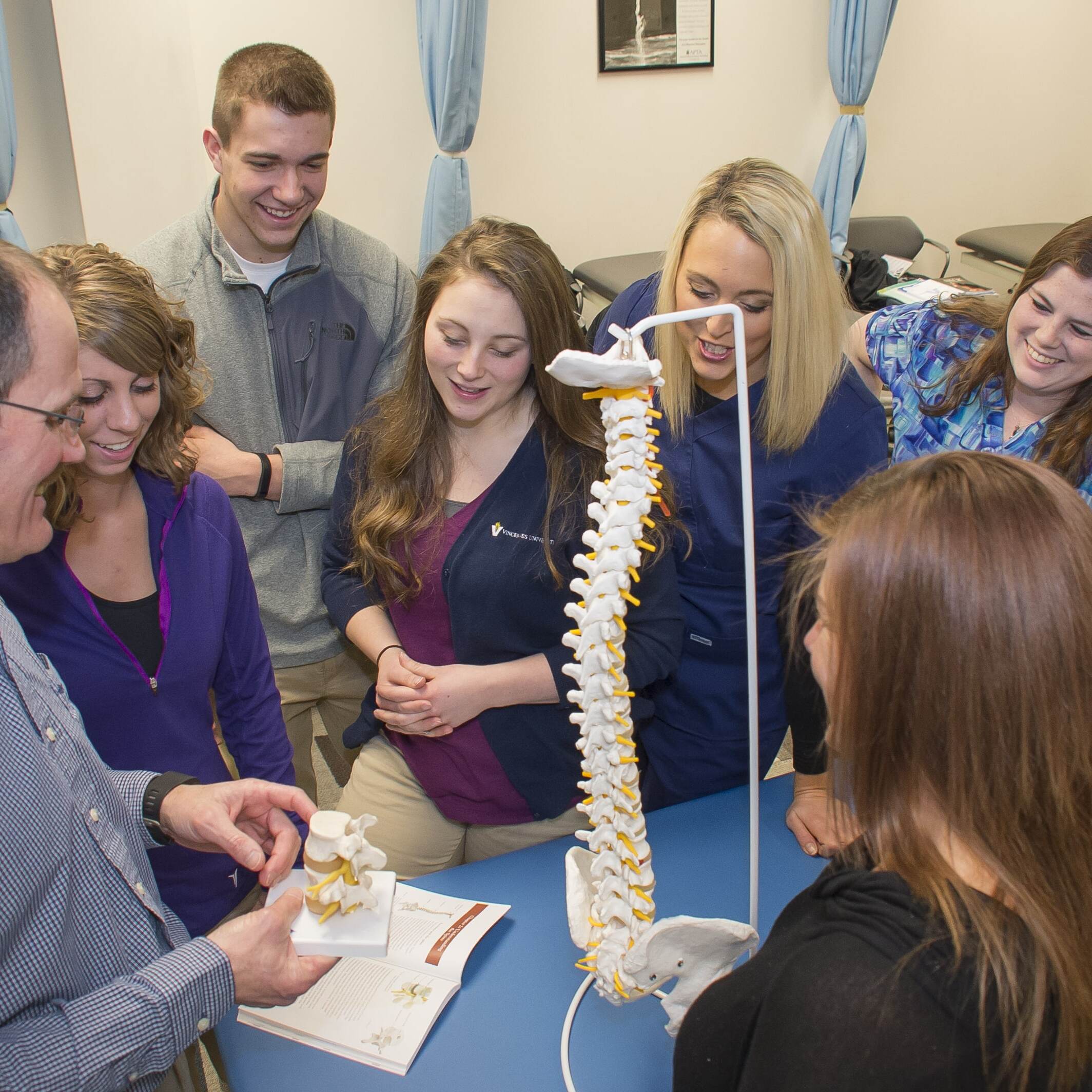 A college professor showing his students the different parts of the human spine