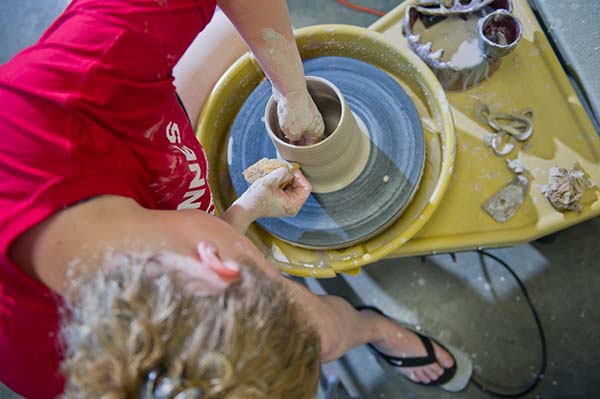 Student works clay on a pottery wheel