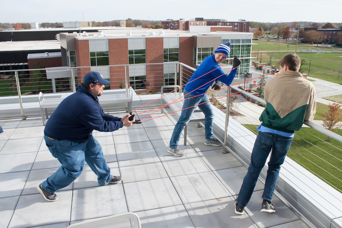 Vincennes University students firing fruit off the roof of Updike Hall with a slingshot