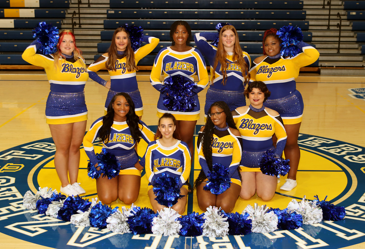 A candid, full shot depicts a cheerleading squad on a gymnasium floor.