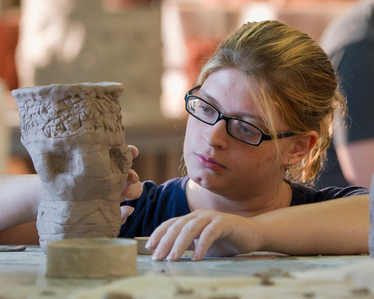 A female student making a sculpture out of clay