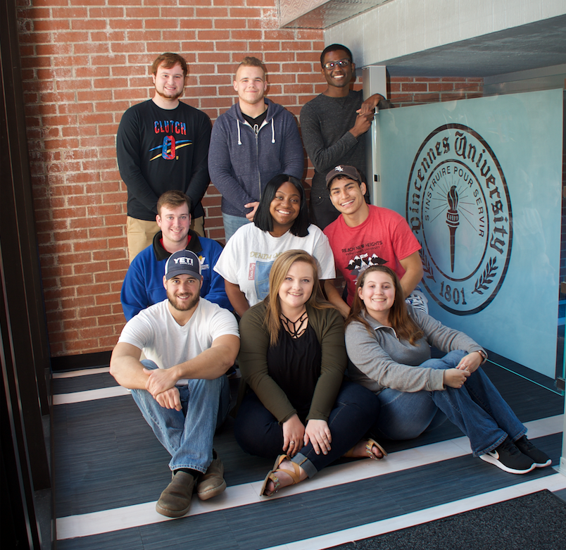 A group of students sitting in front of a brick wall
