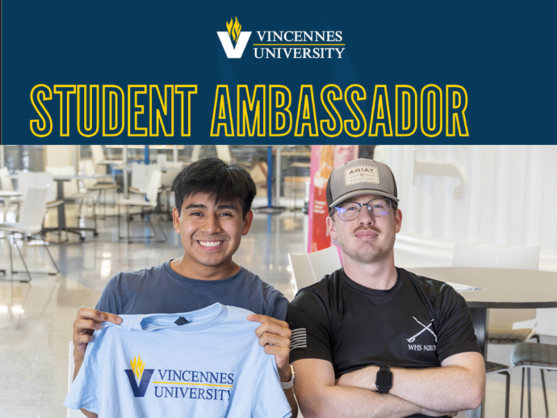 Two students, one holding up a VU shirt.
