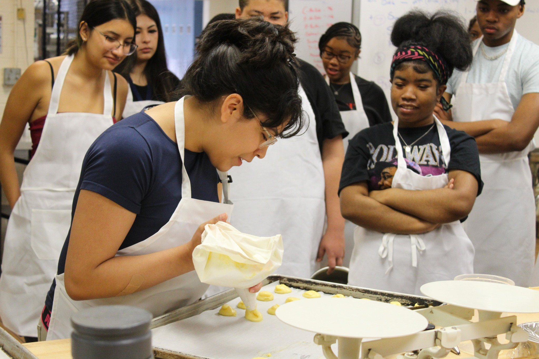A latina student creates their culinary treat during class